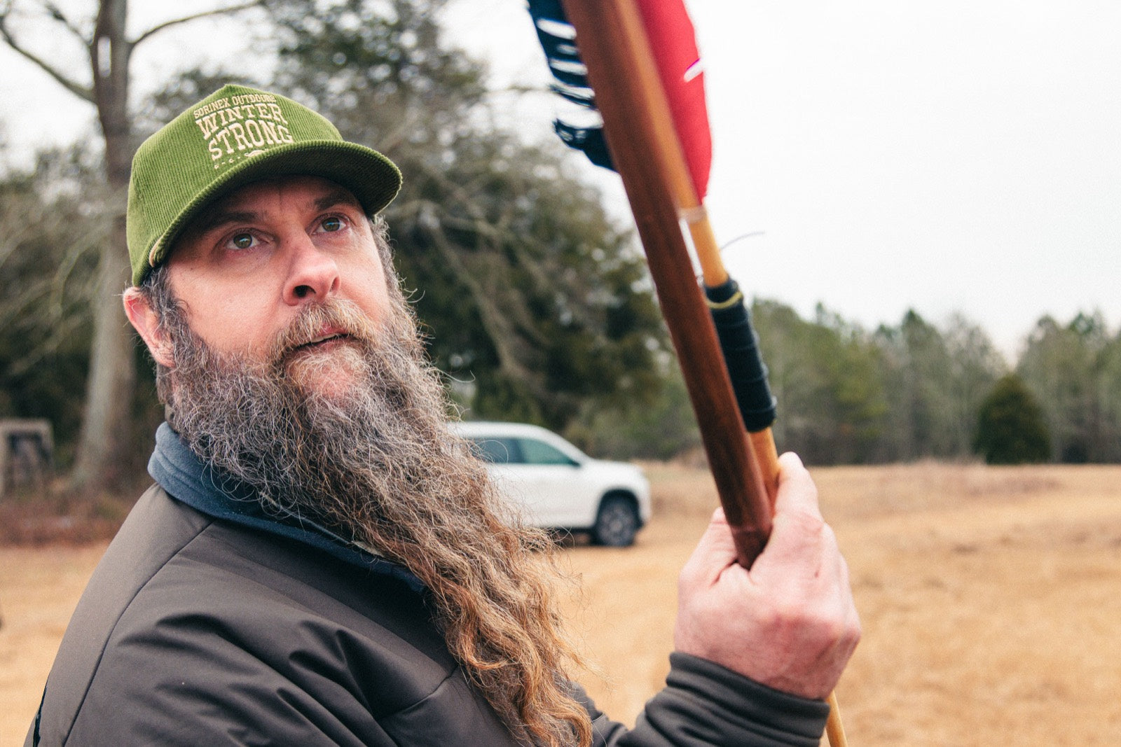 Camp counselor in a custom corduroy hat holding an atlatl