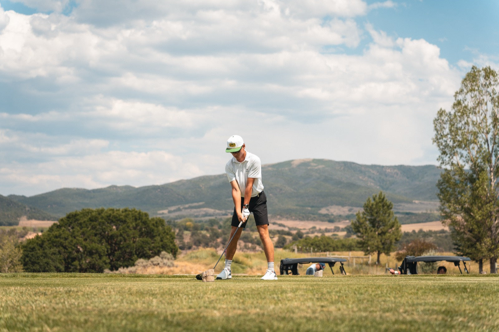 Golfer teeing off in a Concho hat at a tournament